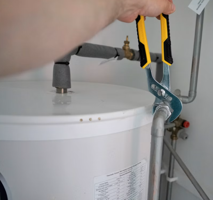 Technician tightening a water heater supply connection during a replacement
